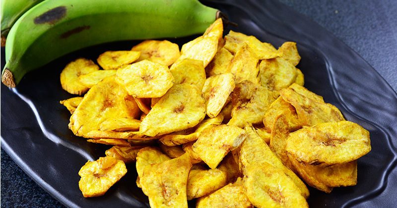 The best foods to dehydrate for long-term storage Dehydrated bananas on a black tray and green bananas beside it.