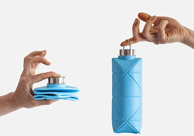 Two hands holding two blue collapsible water bottles, with one bottle collapsed and one bottle ready to use. 