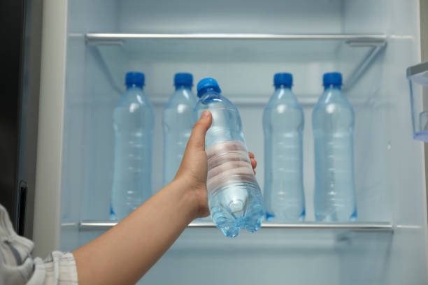 How long can you store tap water A hand holding a fresh tap water bottle for storage in the freezer.