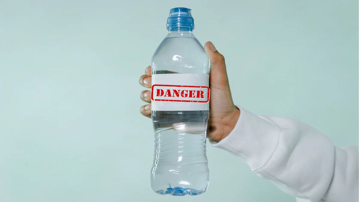 Does water expire in glass bottles A hand holding a plastic bottled water with a "danger" sign.
